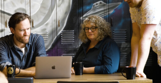 Rocket55 Team Members gather around a computer to bring solutions together